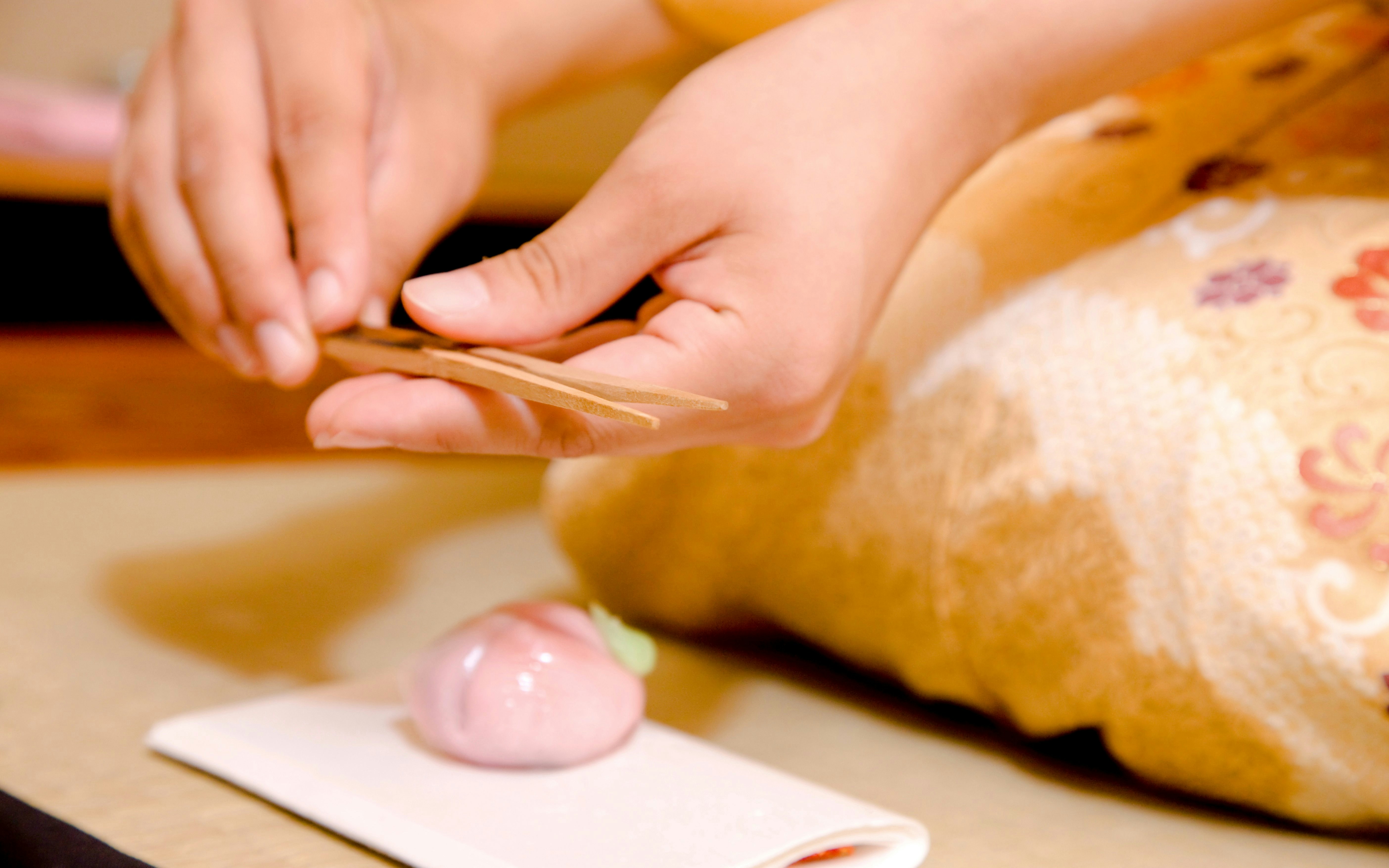Hands crafting traditional Japanese wagashi sweets on a tray.