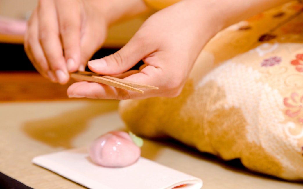 Hands crafting traditional Japanese wagashi sweets on a tray.
