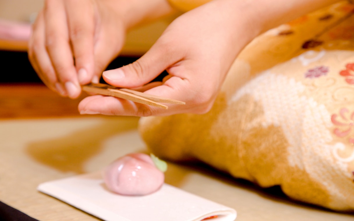 Hands crafting traditional Japanese wagashi sweets on a tray.