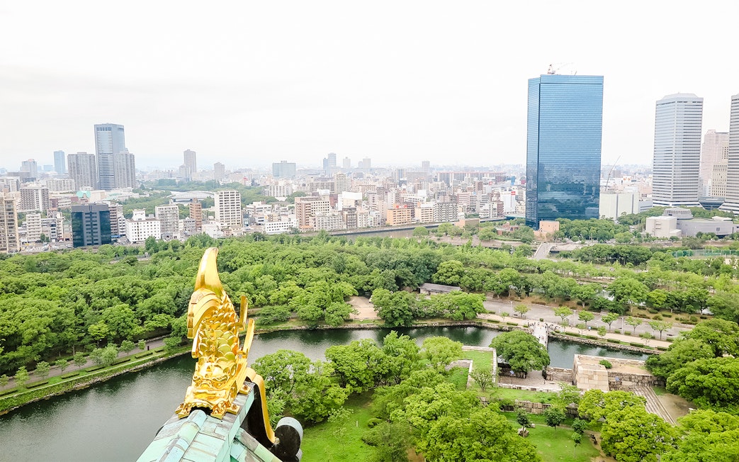 View from Osaka Castle over cityscape and lush greenery.