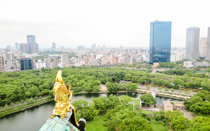 View from Osaka Castle over cityscape and lush greenery.