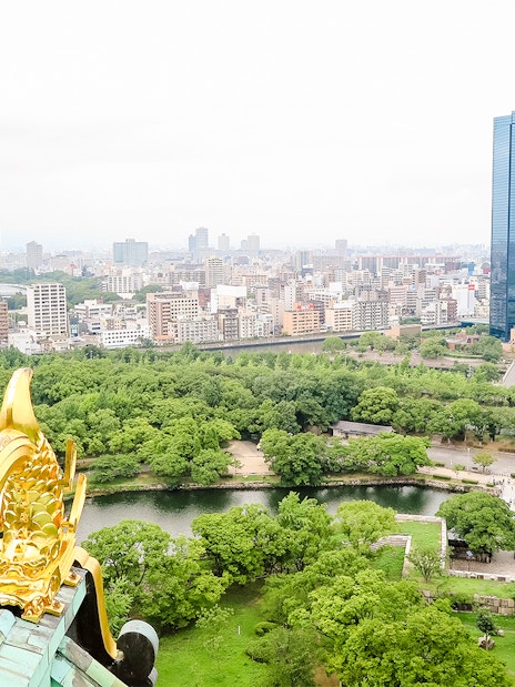 View from Osaka Castle over cityscape and lush greenery.