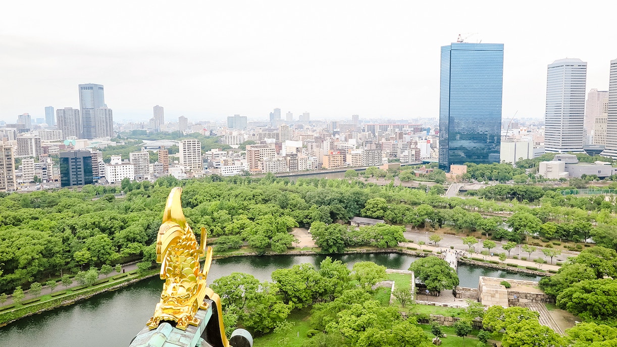 View from Osaka Castle over cityscape and lush greenery.