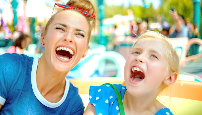 Adults and child enjoying a ride at a theme park.