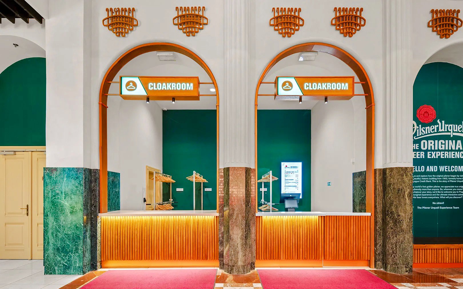 Cloakroom area at Prague Pilsner Urquell Experience with green and orange decor.