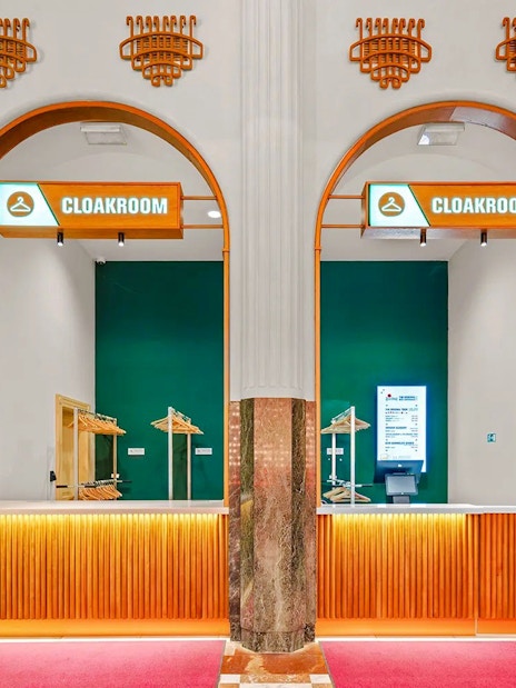 Cloakroom area at Prague Pilsner Urquell Experience with green and orange decor.