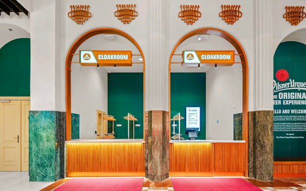 Cloakroom area at Prague Pilsner Urquell Experience with green and orange decor.