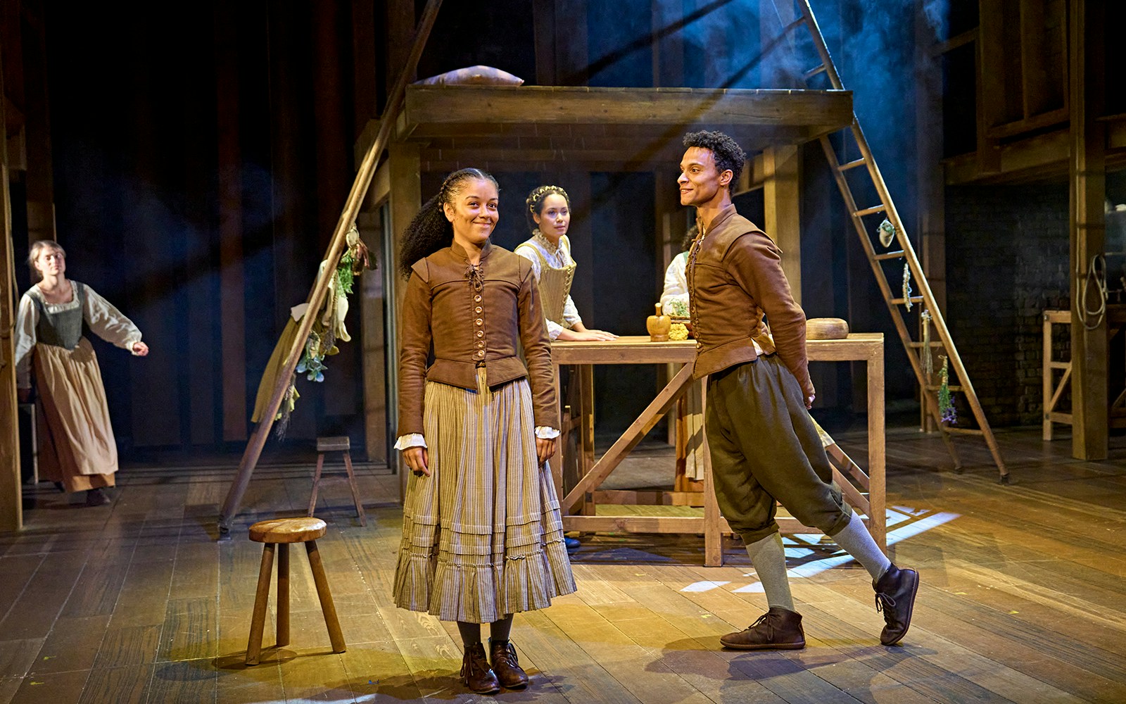 Actors performing a scene from "Hamnet" on stage with period costumes.