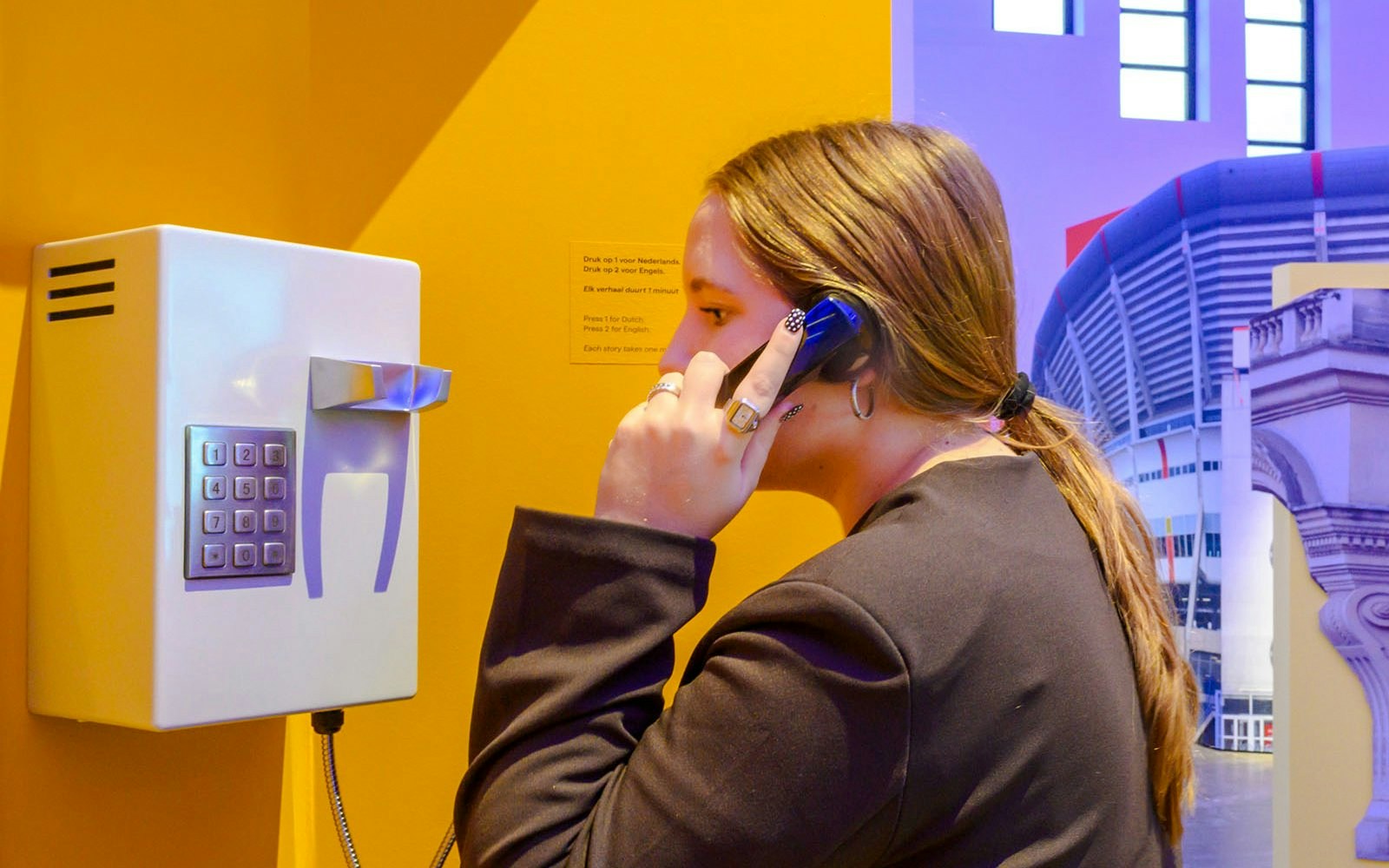 Person using a phone at the Amsterdam in Motion exhibit.