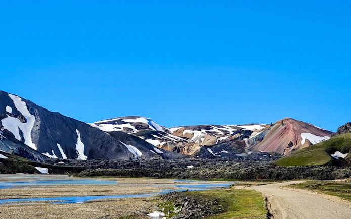 Landmannalaugar Highlands with colorful rhyolite mountains and a winding dirt road in Iceland.