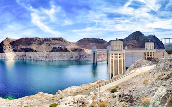 Hoover Dam with pathway leading to Colorado River bank on a sunny morning.