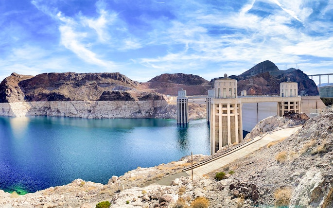 Hoover Dam with pathway leading to Colorado River bank on a sunny morning.