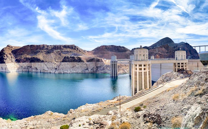 Hoover Dam with pathway leading to Colorado River bank on a sunny morning.