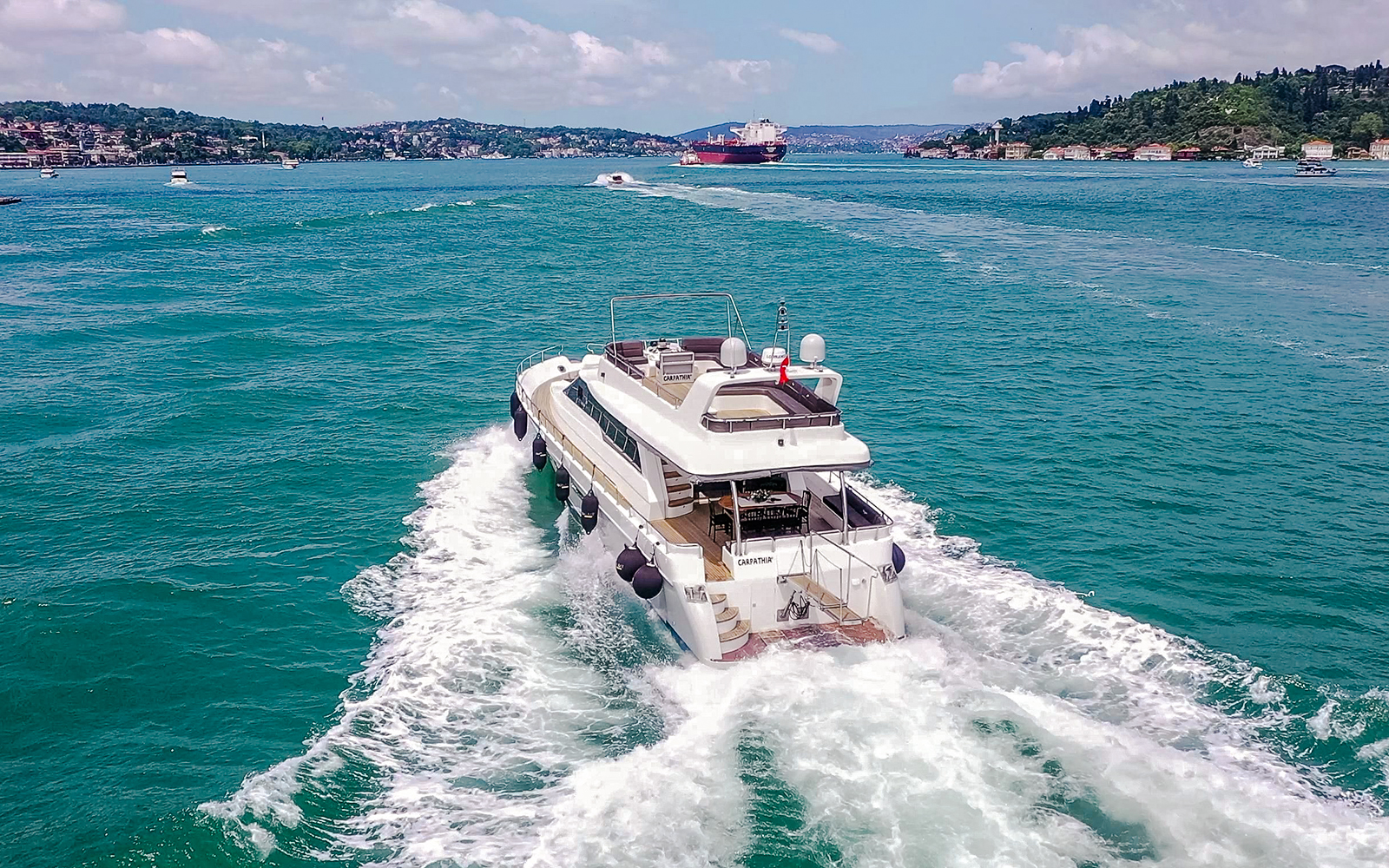 Luxury yacht cruising on the Bosphorus with Istanbul skyline in the background.