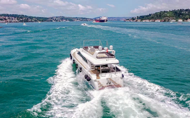 Luxury yacht cruising on the Bosphorus with Istanbul skyline in the background.