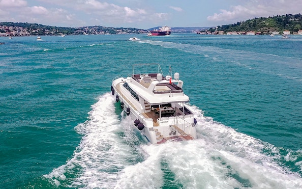 Luxury yacht cruising on the Bosphorus with Istanbul skyline in the background.