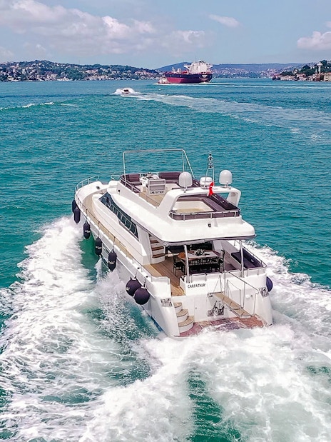 Luxury yacht cruising on the Bosphorus with Istanbul skyline in the background.