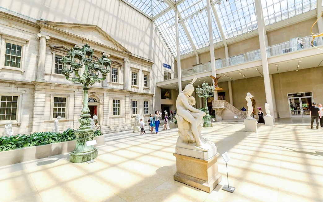 Met Museum interior with sculptures and visitors on the Pre-Orientation Tour.