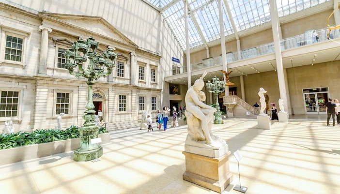Met Museum interior with sculptures and visitors on the Pre-Orientation Tour.