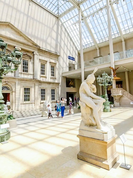 Met Museum interior with sculptures and visitors on the Pre-Orientation Tour.