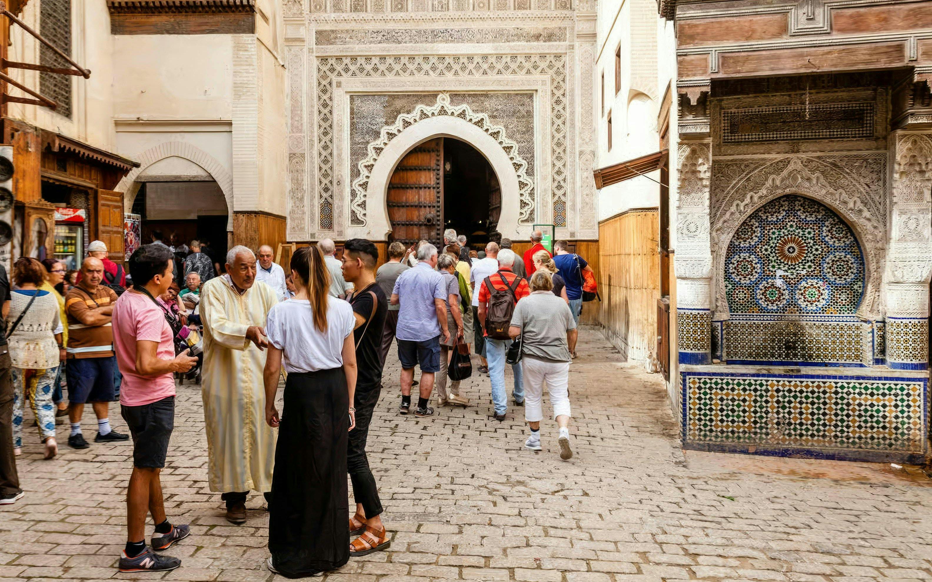 Visitors entering Al Attarine Madrasa in Fes Medina, Morocco.