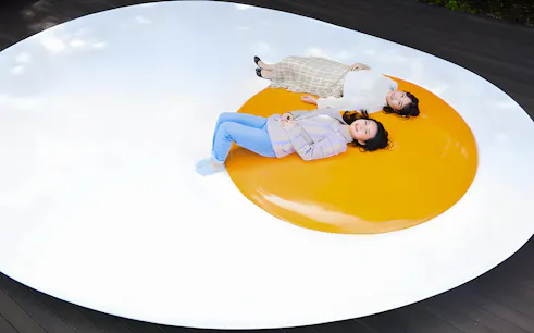 Visitors lying on a large egg sculpture at The Hakone Open-Air Museum.