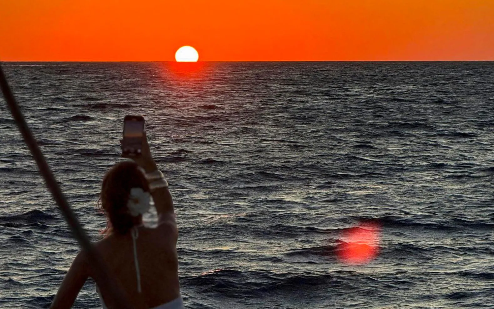 Person photographing sunset over the sea on Heraklion catamaran cruise.
