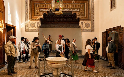 Tour group exploring ornate room in Bahia Palace, Marrakech.