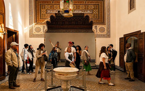 Tour group exploring ornate room in Bahia Palace, Marrakech.