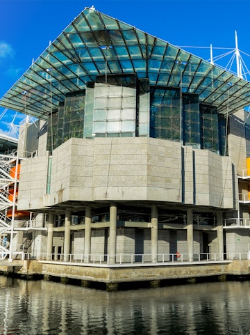Modern architecture of Lisbon Oceanarium building, Portugal, reflecting on water.