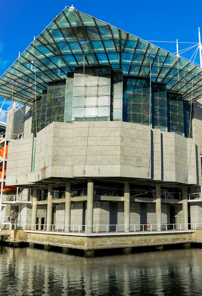 Modern architecture of Lisbon Oceanarium building, Portugal, reflecting on water.