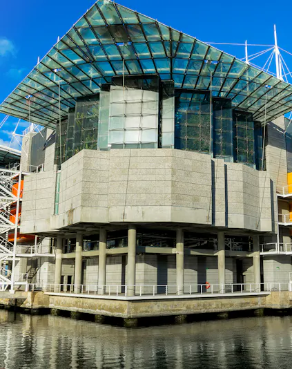 Modern architecture of Lisbon Oceanarium building, Portugal, reflecting on water.
