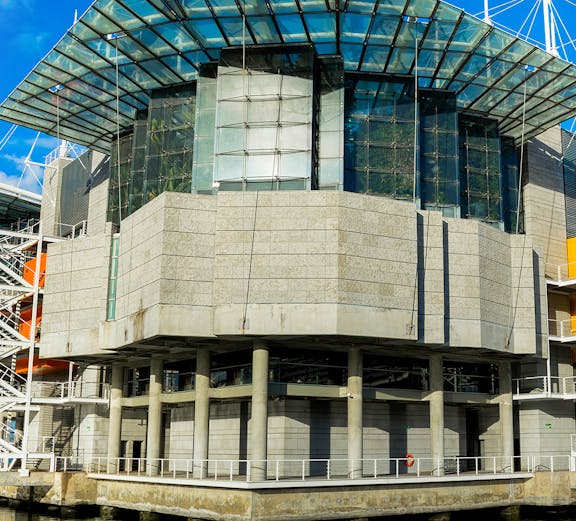 Modern architecture of Lisbon Oceanarium building, Portugal, reflecting on water.