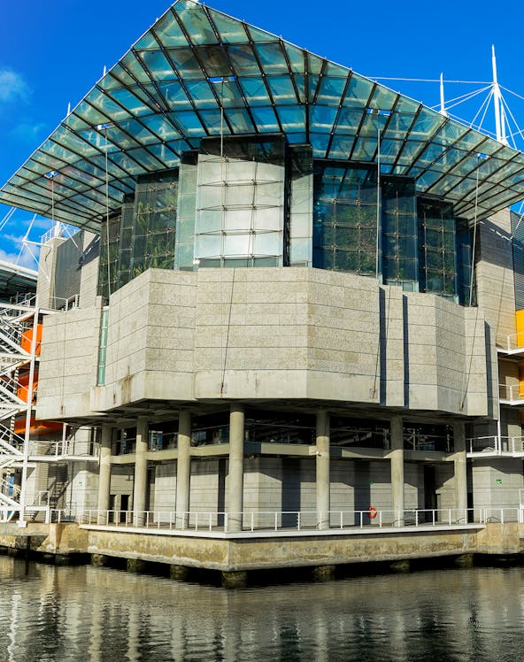 Modern architecture of Lisbon Oceanarium building, Portugal, reflecting on water.