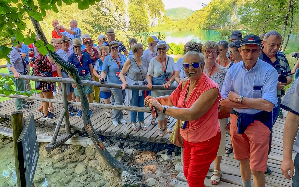 Tour guide leading visitors on a wooden path at Plitvice Lakes, Croatia.