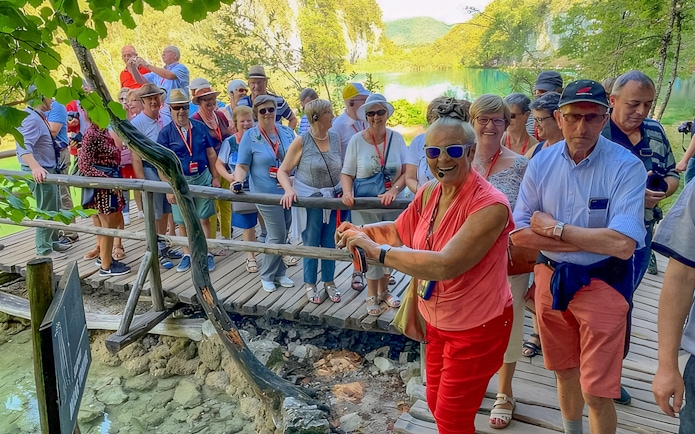 Tour guide leading visitors on a wooden path at Plitvice Lakes, Croatia.