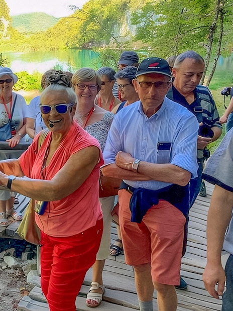 Tour guide leading visitors on a wooden path at Plitvice Lakes, Croatia.