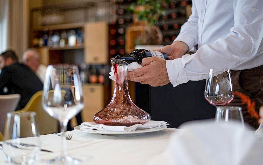 Wine being poured into a decanter during Berat City & Belshi Lake day trip.