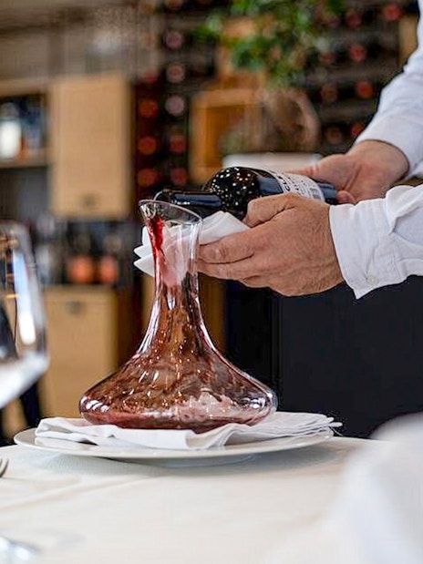 Wine being poured into a decanter during Berat City & Belshi Lake day trip.