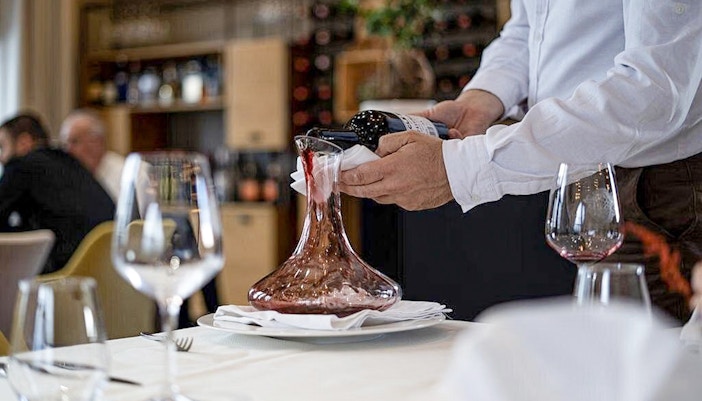 Wine being poured into a decanter during Berat City & Belshi Lake day trip.