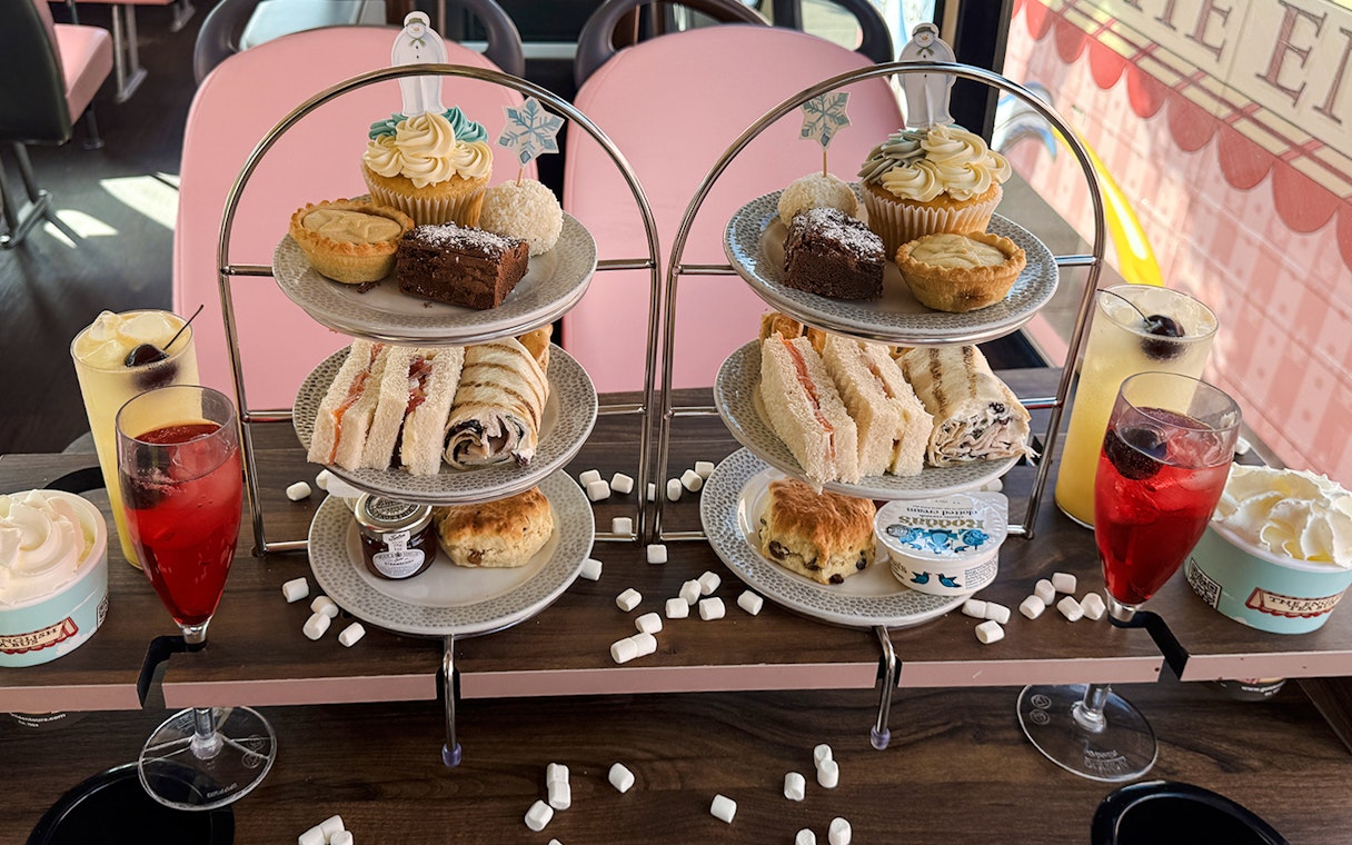 Afternoon tea spread with sandwiches, pastries, and drinks on The Snowman Official Afternoon Tea Bus.