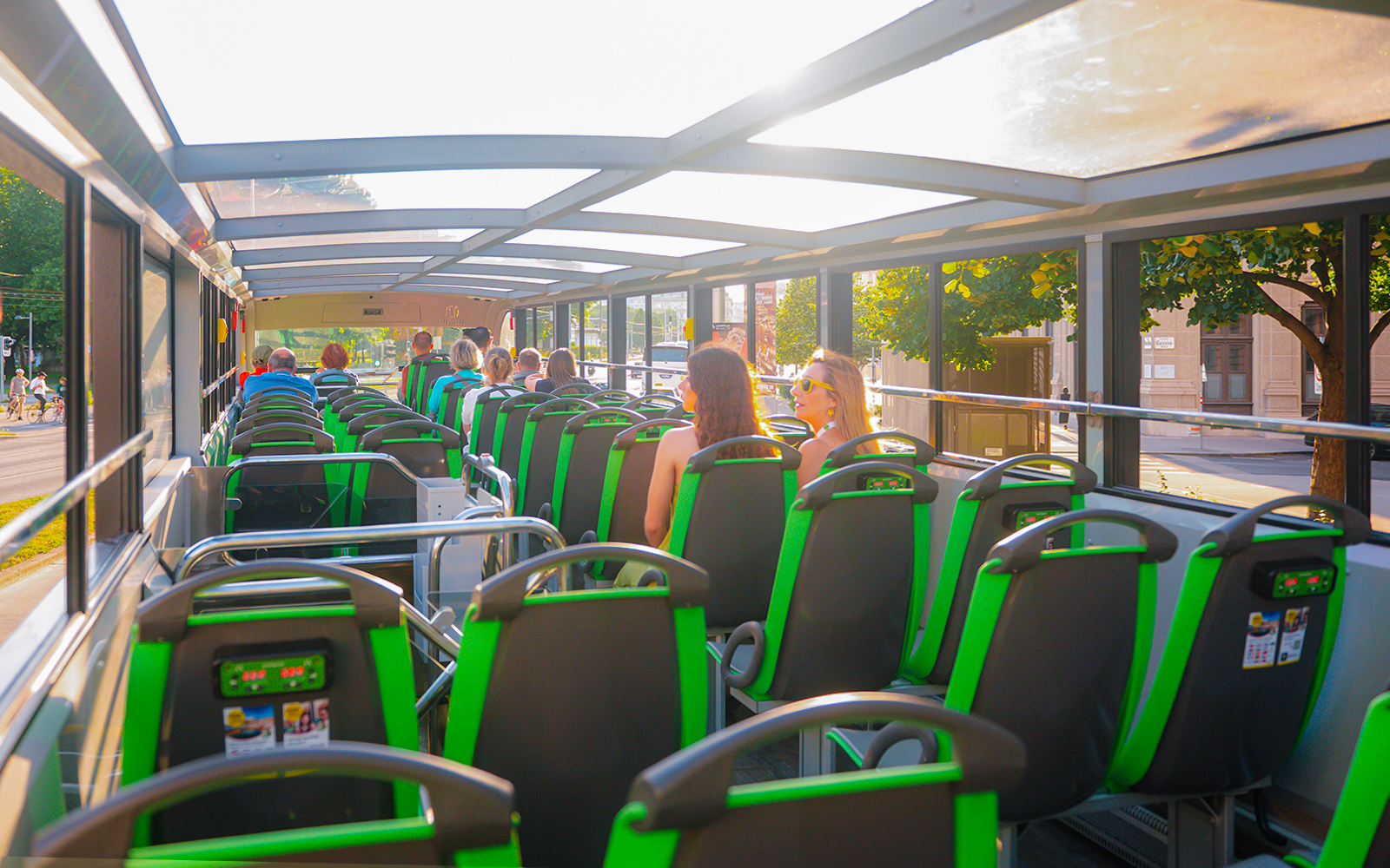 Tourists seated on an open-top Vienna sightseeing bus.