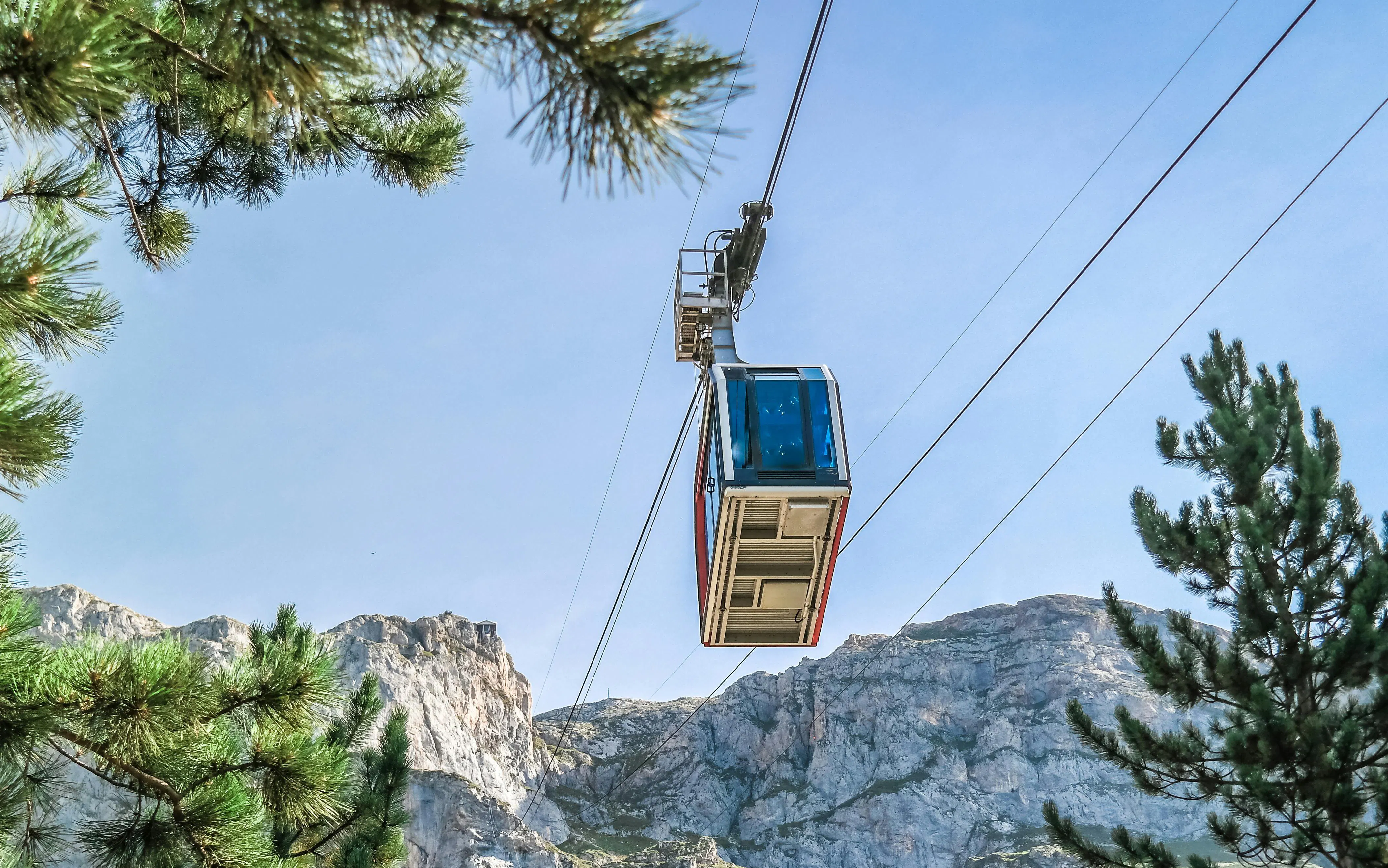 Cable car ascending in Picos de Europa, Spain, with mountain backdrop.