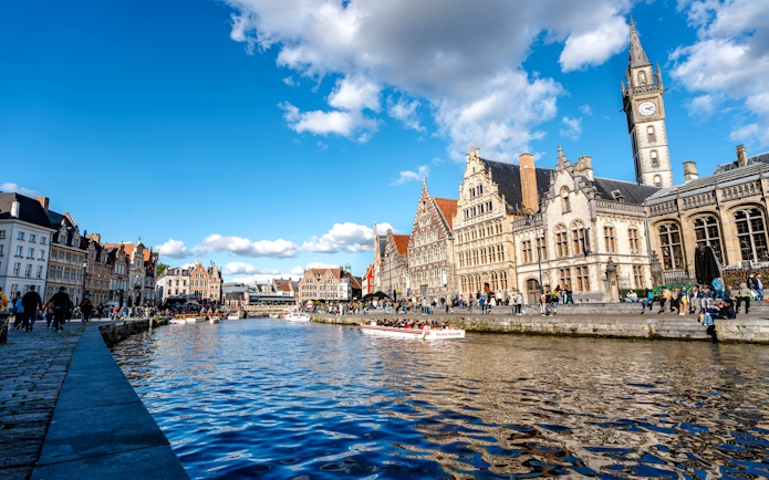 Boating on the Leie River in Ghent with historic buildings and clock tower in view.