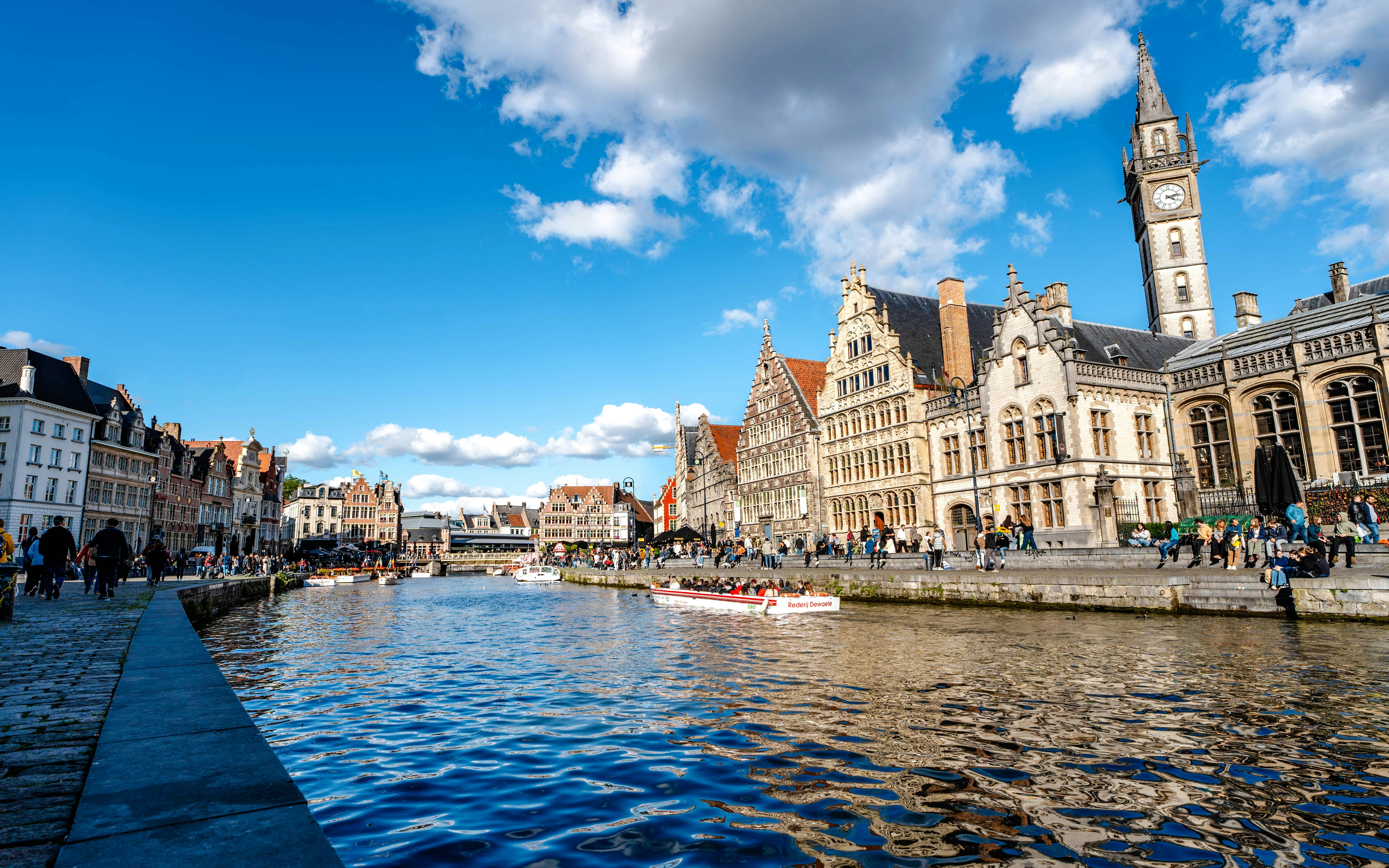 Boating on the Leie River in Ghent with historic buildings and clock tower in view.