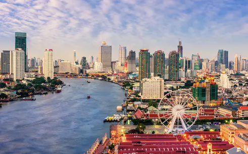 Bangkok skyline with Chao Phraya River and Ferris wheel, highlighting cityscape for private airport transfer.