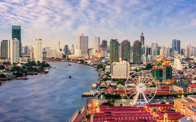 Bangkok skyline with Chao Phraya River and Ferris wheel, highlighting cityscape for private airport transfer.