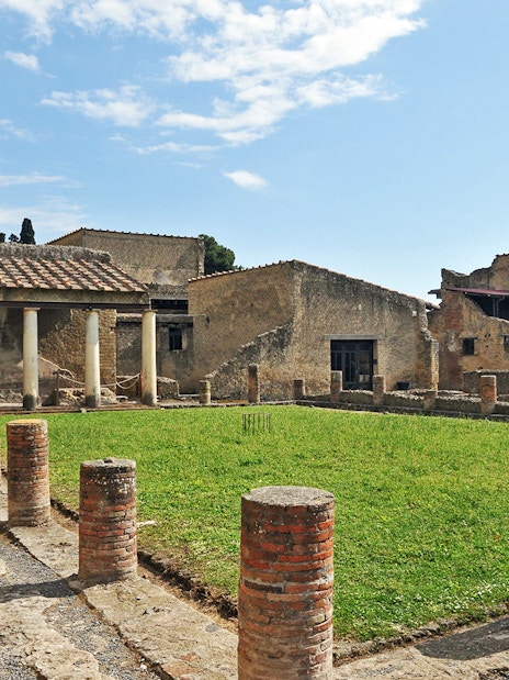 Ruins of Herculaneum with ancient columns and grassy courtyard in Italy.
