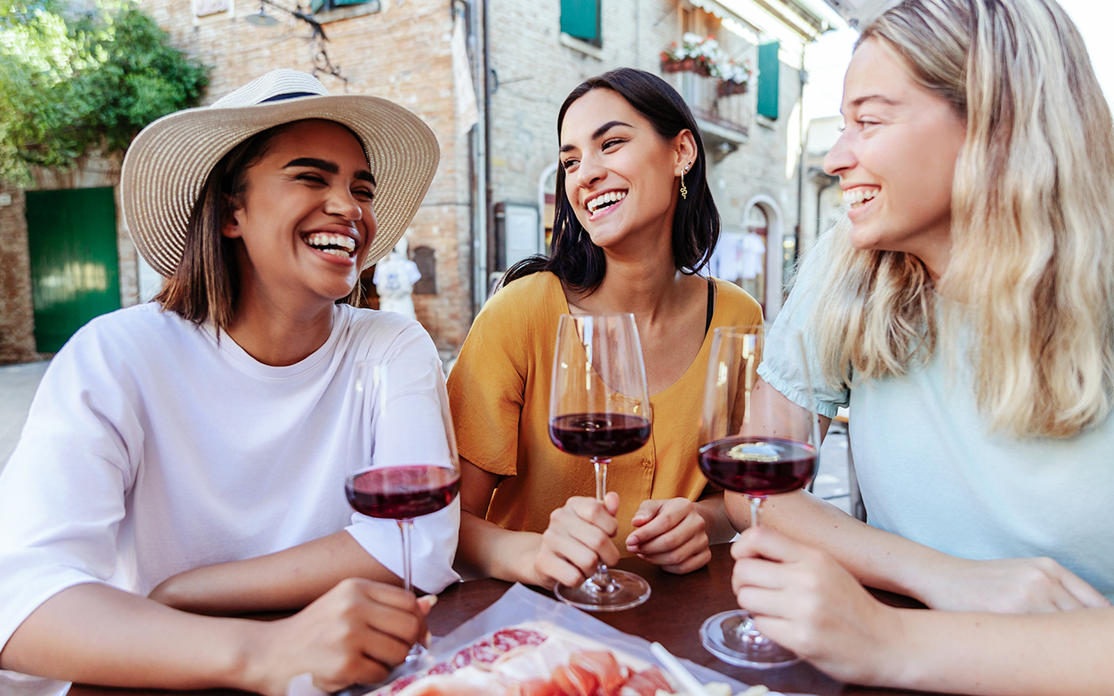 Friends enjoying wine at an outdoor café in a European village.