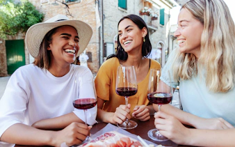 Friends enjoying wine at an outdoor café in a European village.